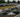 A line of drift cars on track with tire smoke during 2025 drift event, paddock tents visible