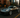 Slammed Nissan 350Z with a wide body kit and huge rear wing rolling through a New York City street at dusk, captured mid corner with motion blur.
