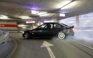 Beginner drifter practicing donuts on a skid pad with a stripped E46 drift car