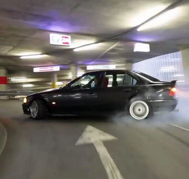 Beginner drifter practicing donuts on a skid pad with a stripped E46 drift car