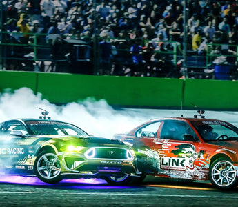 Drivers drifting at a grassroots drift event with spectators watching near the track in 2025
