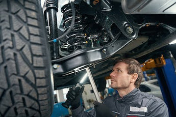 Mechanic inspecting worn inner tie rod end on a lowered drift car