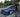 Adam LZ's BMW E36 drift car with SLR angle kit during a tandem drift event, Adam LZ standing next to his car.