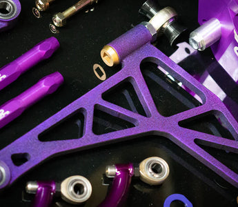 SLR 350Z angle kit components laid out on a shop bench with control arms, knuckles, and tie rods visible