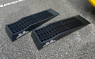 Car ramps for oil change laying on ground next to a car