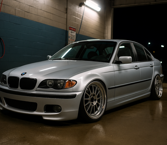 Lowered BMW E46 on coilovers at a night car wash, featuring aggressive stance, deep wheels, and performance suspension setup.