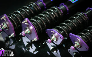 Close up shot of purple G37 coilovers on a black reflective table