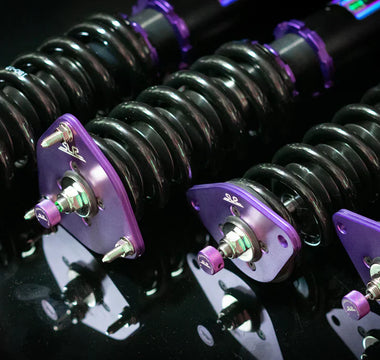 Close up shot of purple G37 coilovers on a black reflective table