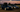 BMW E46 and C5 Corvette lined up in the paddock, tires mounted, ready for drifting under trackside lights