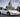 Matte white C5 Corvette slammed with bolt on widebody overfenders parked in front of Magic Kingdom castle with aggressive stance and aftermarket wheels in a 16 by 9 automotive photo