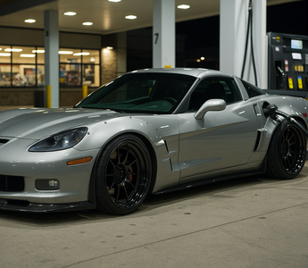 Slammed widebody C6 Corvette Z06 parked at a gas station pump at night, featuring lowered stance, aggressive aero, deep-dish wheels, and performance-focused styling.