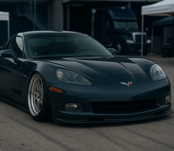 Slammed Chevrolet C6 Corvette on adjustable coilovers at a motorsport paddock with aggressive stance and camber plates visible.