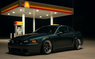 Slammed SN95 New Edge Mustang parked under Shell gas station lights at night, showcasing its low stance and SN95 coilovers.