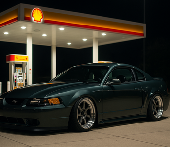 Slammed SN95 New Edge Mustang parked under Shell gas station lights at night, showcasing its low stance and SN95 coilovers.