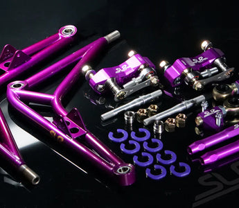 A full purple angle kit laying on a table with control arms, steering knuckle adapters, lollipops, tie rods, steering stops and more