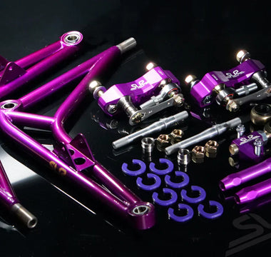 A full purple angle kit laying on a table with control arms, steering knuckle adapters, lollipops, tie rods, steering stops and more