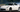 Side shot of a drift car with wide angle, coilovers, and smoke-filled corner entry