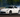Side shot of a drift car with wide angle, coilovers, and smoke-filled corner entry
