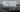 Cars lined up in grid at a drift event with drivers and tire smoke in background