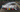 A line of 10 cars from a drone shot, on a florida race track drifting with crowds all around. Title over the image says DRIFT EVENTS