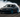 A professional drift car sliding sideways at full lock with smoke pouring from the rear tires during a drift event