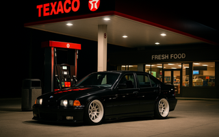 Slammed BMW E36 sedan on coilovers for E36 parked at a Texaco gas station under bright canopy lights at night.