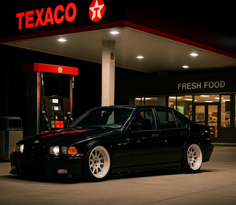 Slammed BMW E36 sedan on coilovers for E36 parked at a Texaco gas station under bright canopy lights at night.