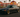 Widebody grey BMW E36 slammed on gold wheels parked in an In-N-Out Burger parking lot at sunset.