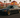 Widebody grey BMW E36 slammed on gold wheels parked in an In-N-Out Burger parking lot at sunset.