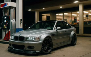 Slammed widebody BMW E46 M3 parked at a gas station pump at night with the front wheels turned, showcasing aggressive stance, deep-dish wheels, and performance drift styling.