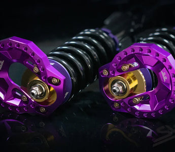 Purple adjustable caster camber plates installed on a BMW E46 front suspension