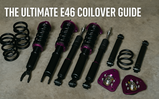 BMW E46 coilover suspension kit laid out on a garage floor, including springs, dampers, and camber plates