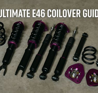 BMW E46 coilover suspension kit laid out on a garage floor, including springs, dampers, and camber plates