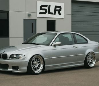 Slammed silver BMW E46 coupe parked in front of an office building.
