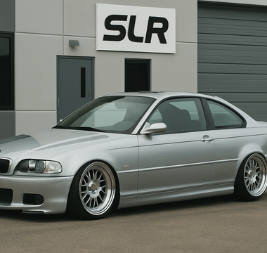 Slammed silver BMW E46 coupe parked in front of an office building.