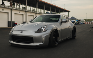 Slammed Nissan 370Z with adjustable coilovers displayed at a motorsport paddock showing camber plates, ride height, and performance stance.