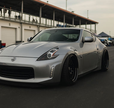 Slammed Nissan 370Z with adjustable coilovers displayed at a motorsport paddock showing camber plates, ride height, and performance stance.