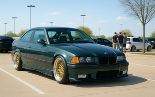 Slammed dark green BMW E36 M3 on gold wheels parked at a daytime Texas car meet in a clean parking lot with people and cars in the background.