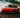 A red 240sx doing a 360 drift on track with smoke coming out of back tires
