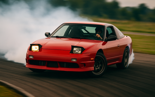A red 240sx doing a 360 drift on track with smoke coming out of back tires