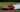 A drift car sliding sideways around a corner on a closed track, kicking up tire smoke