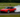 A drift car sliding sideways around a corner on a closed track, kicking up tire smoke