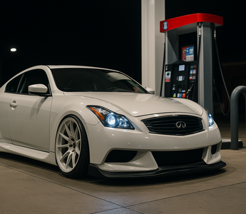 Slammed Infiniti G37S with a wide body kit parked at a gas station pump at night under neon lighting, with reflections on wet pavement highlighting its low stance and performance coilover setup.