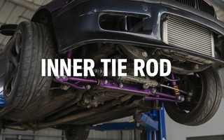 A BMW E36 up on a lift showing the underside of the car with tie rods and control arms