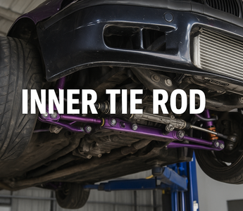 A BMW E36 up on a lift showing the underside of the car with tie rods and control arms