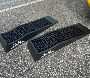 Low profile auto ramps on driveway next to race car