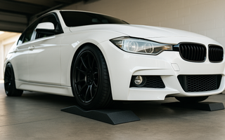 Low profile car ramps under a lowered sports car in a garage, showing the shallow incline and bumper-safe design for maintenance access.