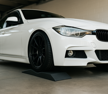 Low profile car ramps under a lowered sports car in a garage, showing the shallow incline and bumper-safe design for maintenance access.
