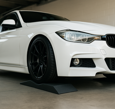 Low profile car ramps under a lowered sports car in a garage, showing the shallow incline and bumper-safe design for maintenance access.