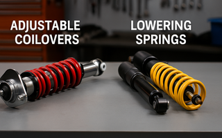 Close-up of adjustable coilovers and lowering springs side by side, mounted on a garage bench for comparison.